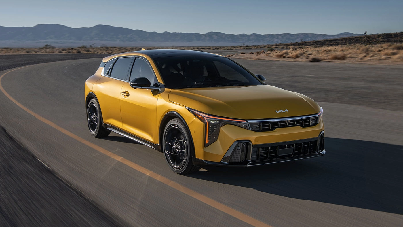 Vue 3/4 avant et lat&eacute;rale du Kia K4 &agrave; hayon 2026 sur route en pleine puissance