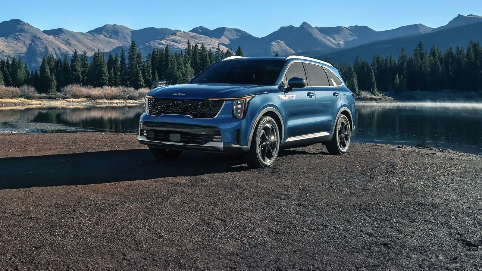 The Kia Sorento hybrid parked in front of a small lake and at the foot of the mountains.