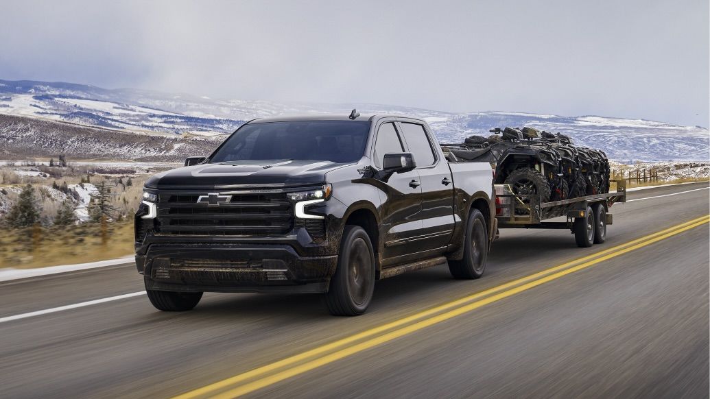 The Chevrolet Silverado 1500 towing a trailer with 4 wheels on it.