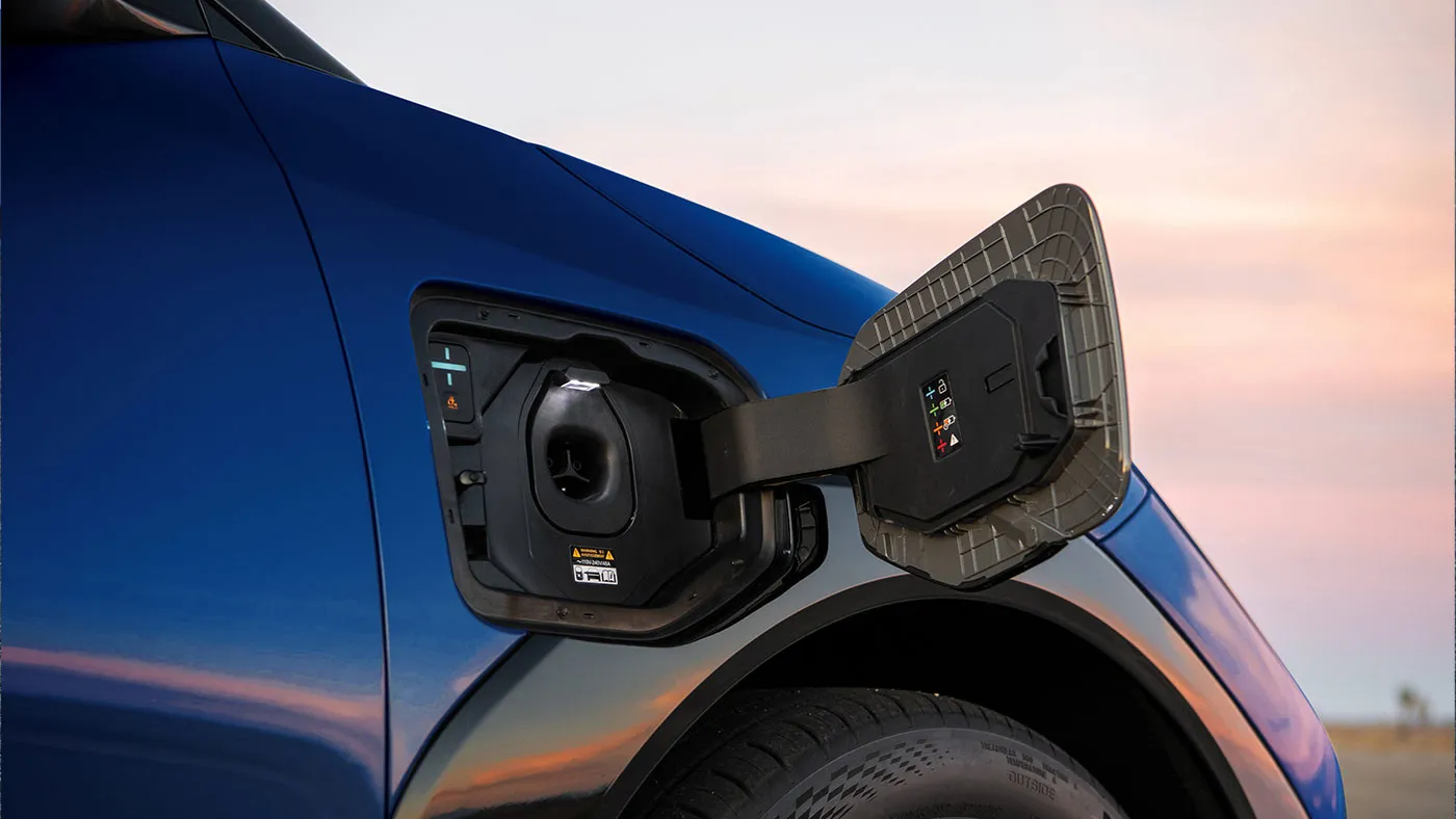 Gros plan sur le port de recharge NACS ouvert d&rsquo;une Kia EV4 &eacute;lectrique bleue.