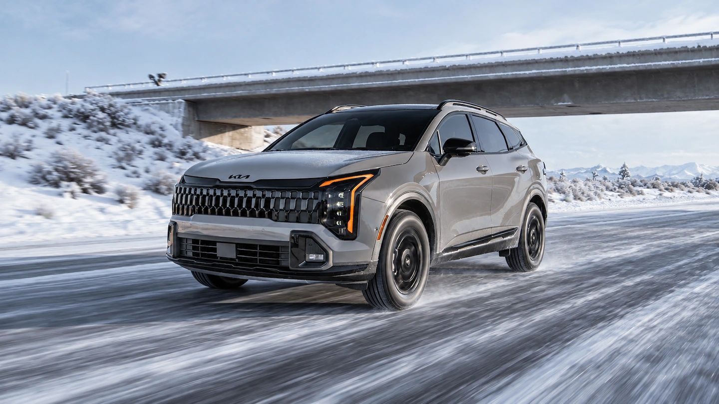 Kia Sportage 2026 en conduite hivernale sur une route enneig&eacute;e.