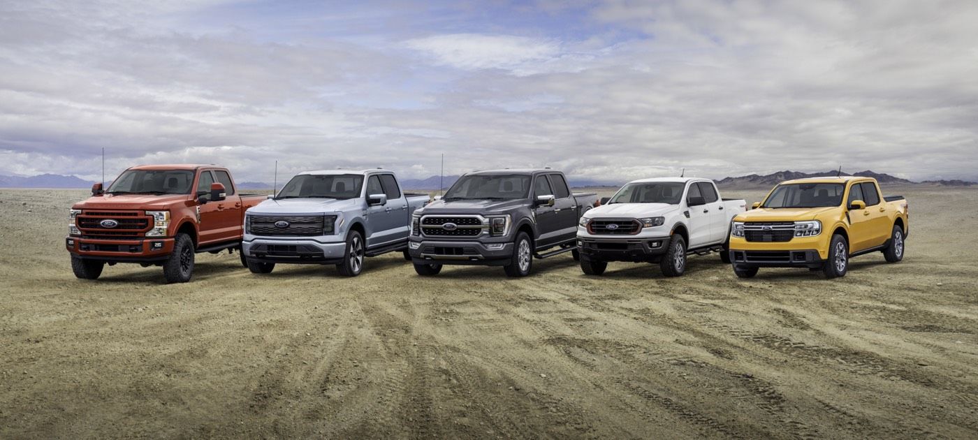 Gamme de cinq camions Ford Maverick 2022 de différentes couleurs garés sur une terre battue