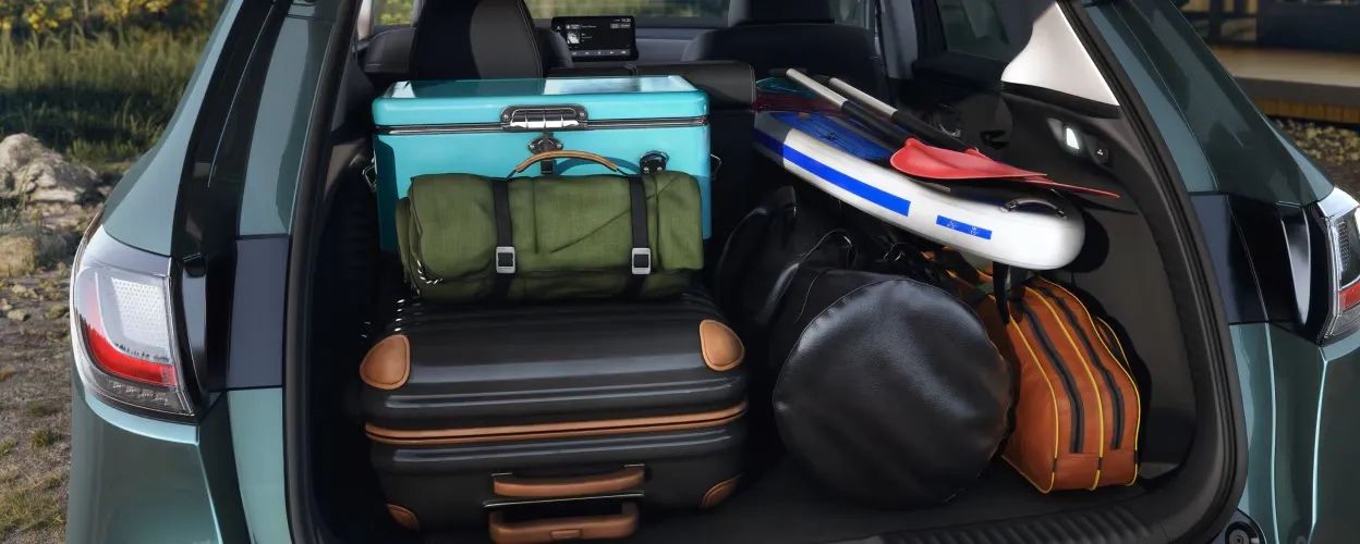 Espace de chargement du Honda HR-V 2026 rempli d’équipement de plein air incluant valises, planche et glacière turquoise.