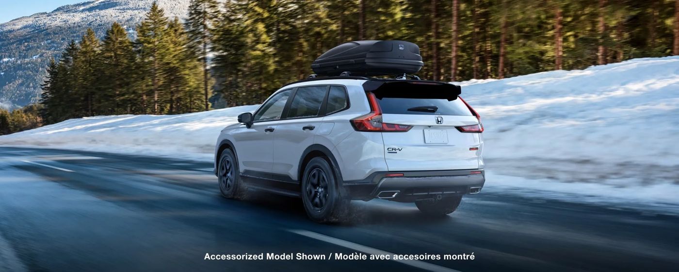 Vue latérale du Honda CR-V 2026 blanc roulant sur une route enneigée, illustrant la traction et la stabilité du VUS compact en conditions hivernales.