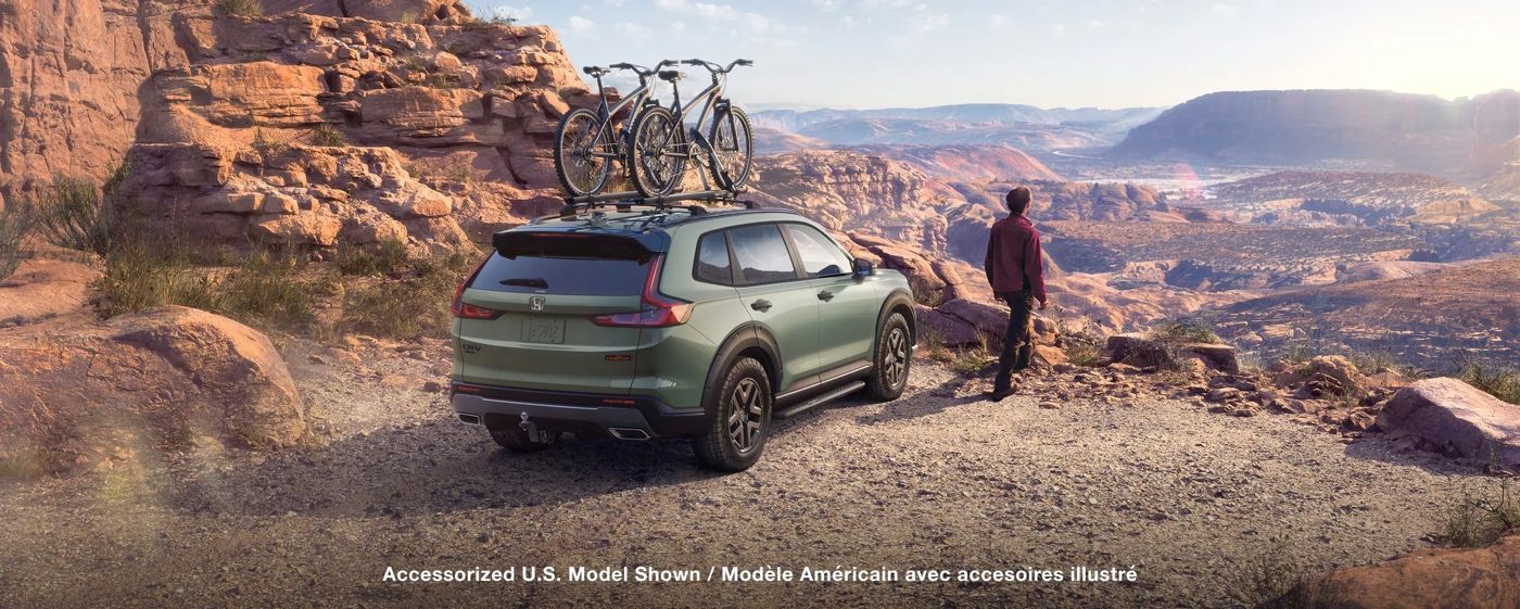 Honda CR-V hybride 2026 TrailSport stationné en paysage rocheux avec vélos sur le toit, illustrant les capacités de plein air du VUS pour les aventures en nature.