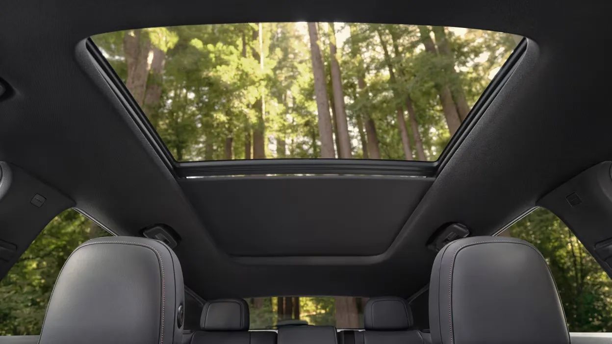 Vue intérieure du toit panoramique du Honda Prologue 2025, laissant entrer la lumière naturelle et offrant une vue dégagée sur la forêt environnante.