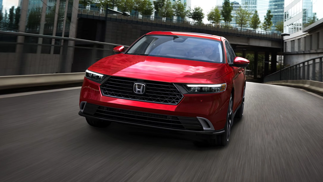 Vue 3/4 avant du Honda Accord hybride sur route en ville, en pleine puissance