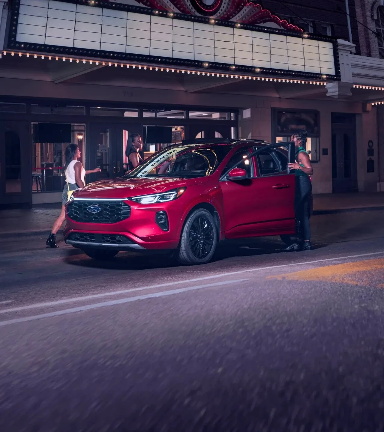 Red 2026 Ford Escape parked in front of a theatre in the evening.