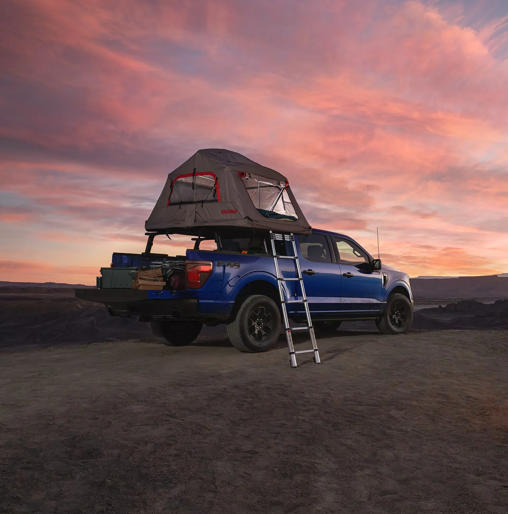 Blue Ford F-150 equipped with a rooftop tent for camping.