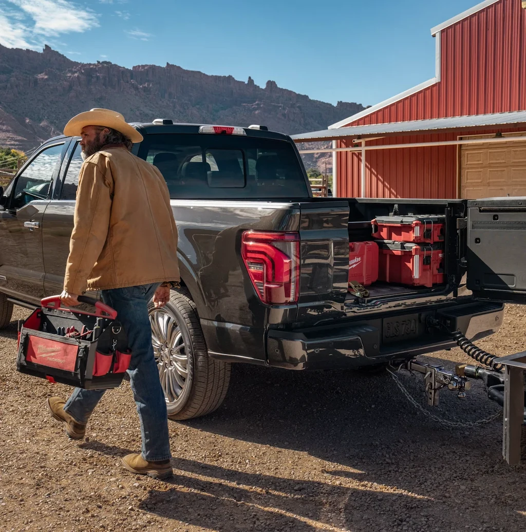 Worker using the bed of a Ford F-150 with tools.