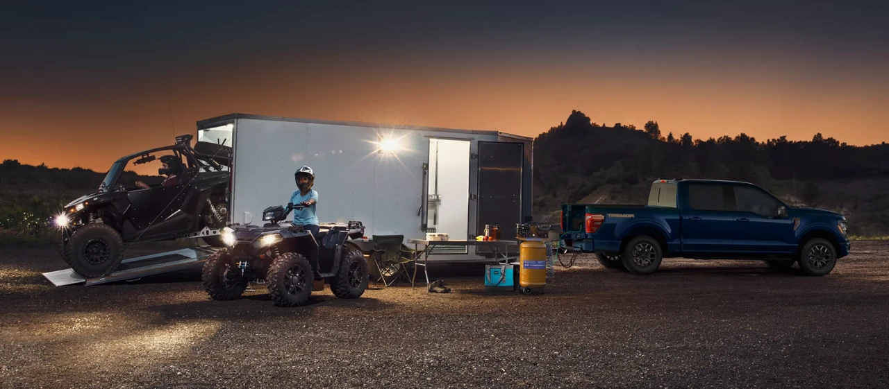 Blue Ford F-150 towing a camper for outdoor leisure.