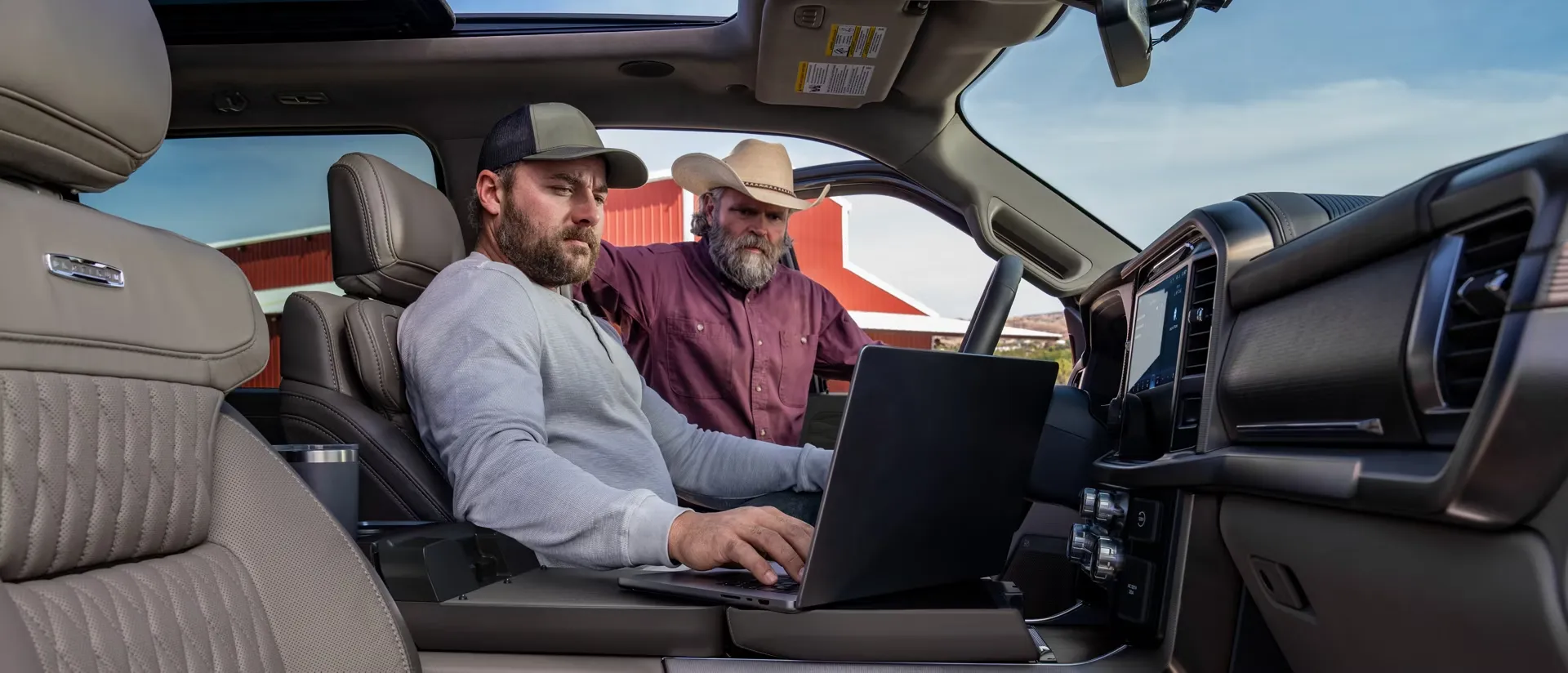 Two workers consulting a computer inside the Ford F-150 cabin.