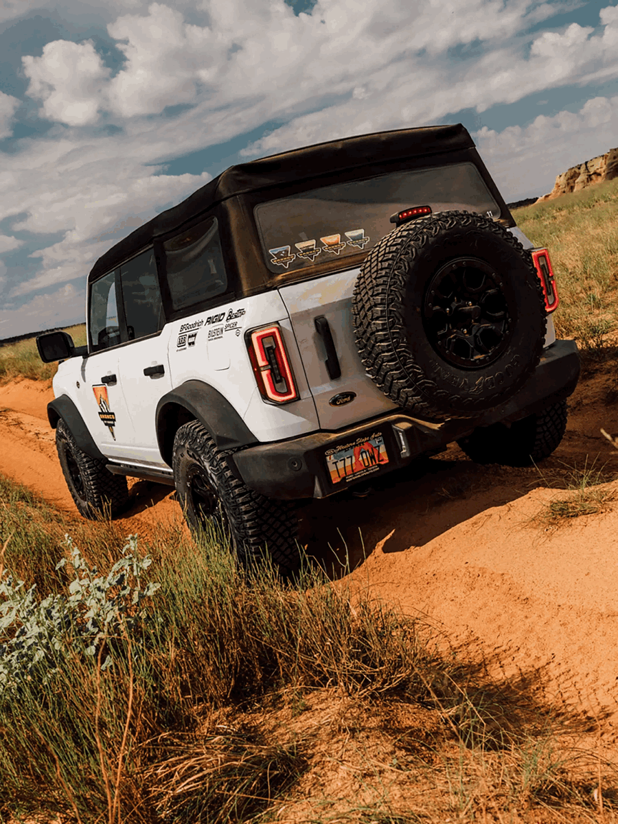 Rear view of a white Ford Bronco on an off-road trail.