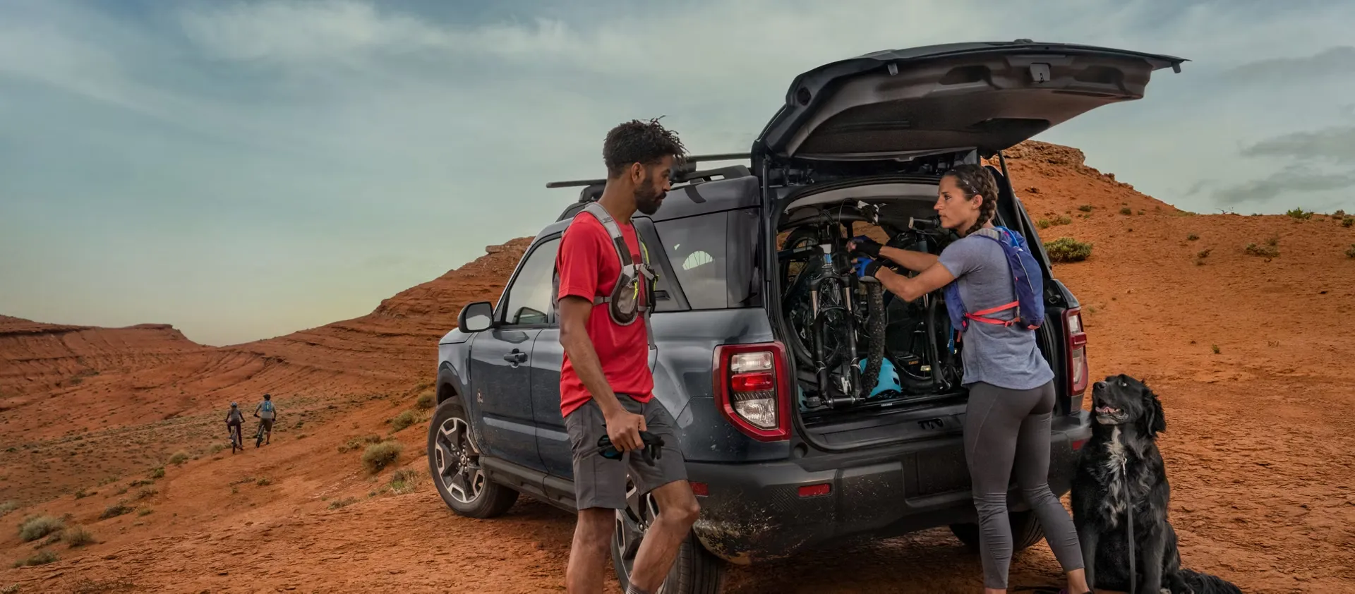 Two cyclists loading their bikes into the cargo area of a Ford Bronco Sport.