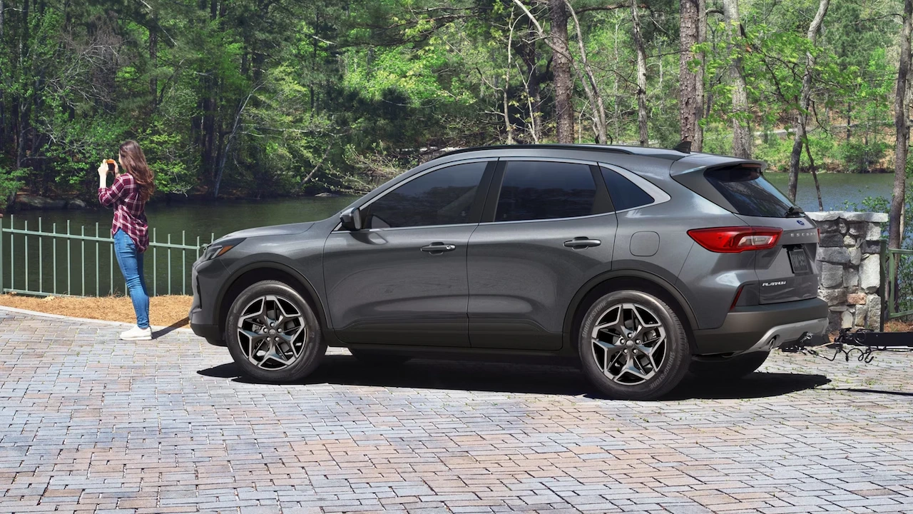 Ford Escape 2026 gris stationné près d’un lac en forêt.