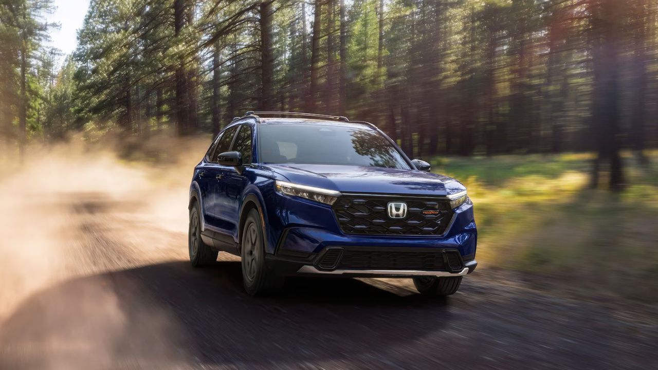 Honda CR-V 2026 bleu roulant sur un chemin en forêt.
