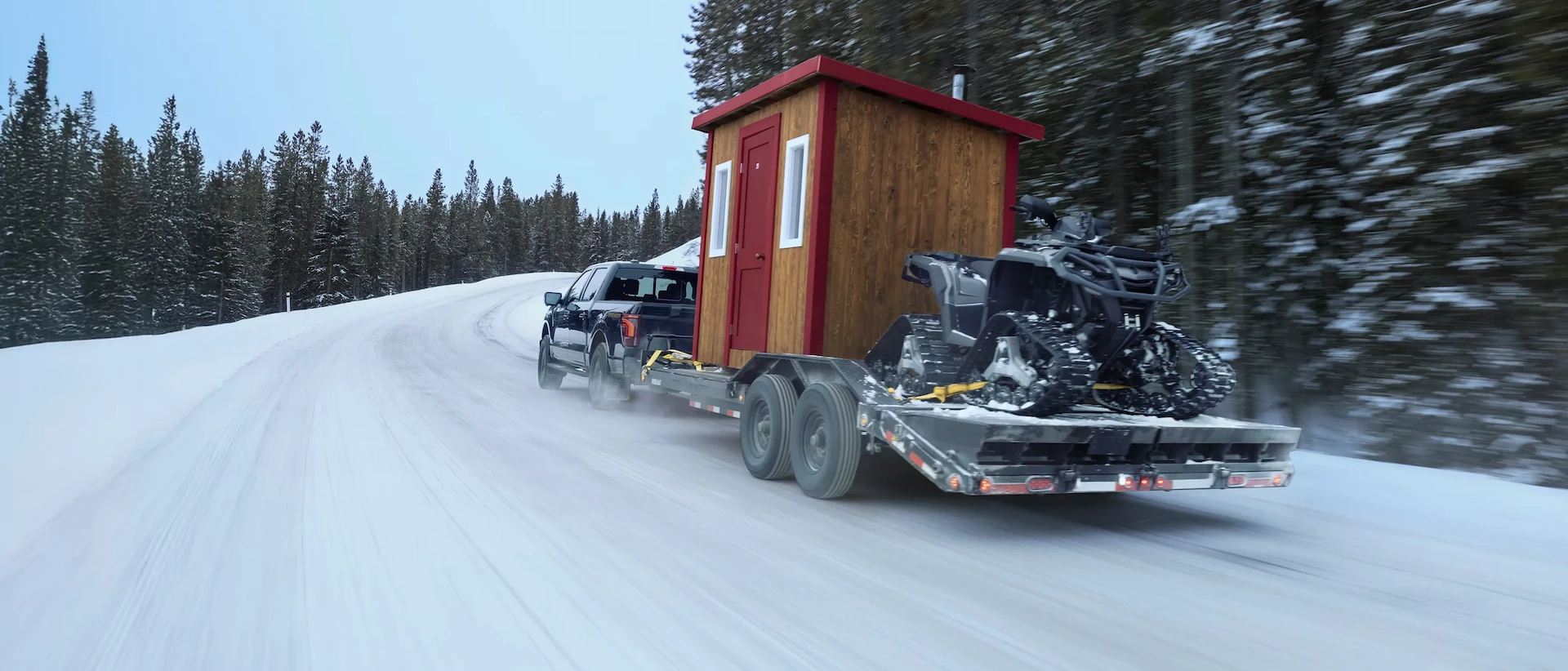 2026 Ford F-150 towing a cabin and snowmobile on a snowy road.