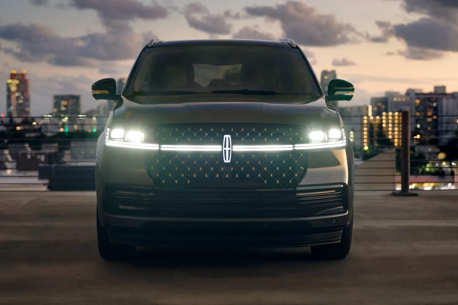 Lincoln Navigator 2027 vu de face devant un paysage urbain au cr&eacute;puscule.