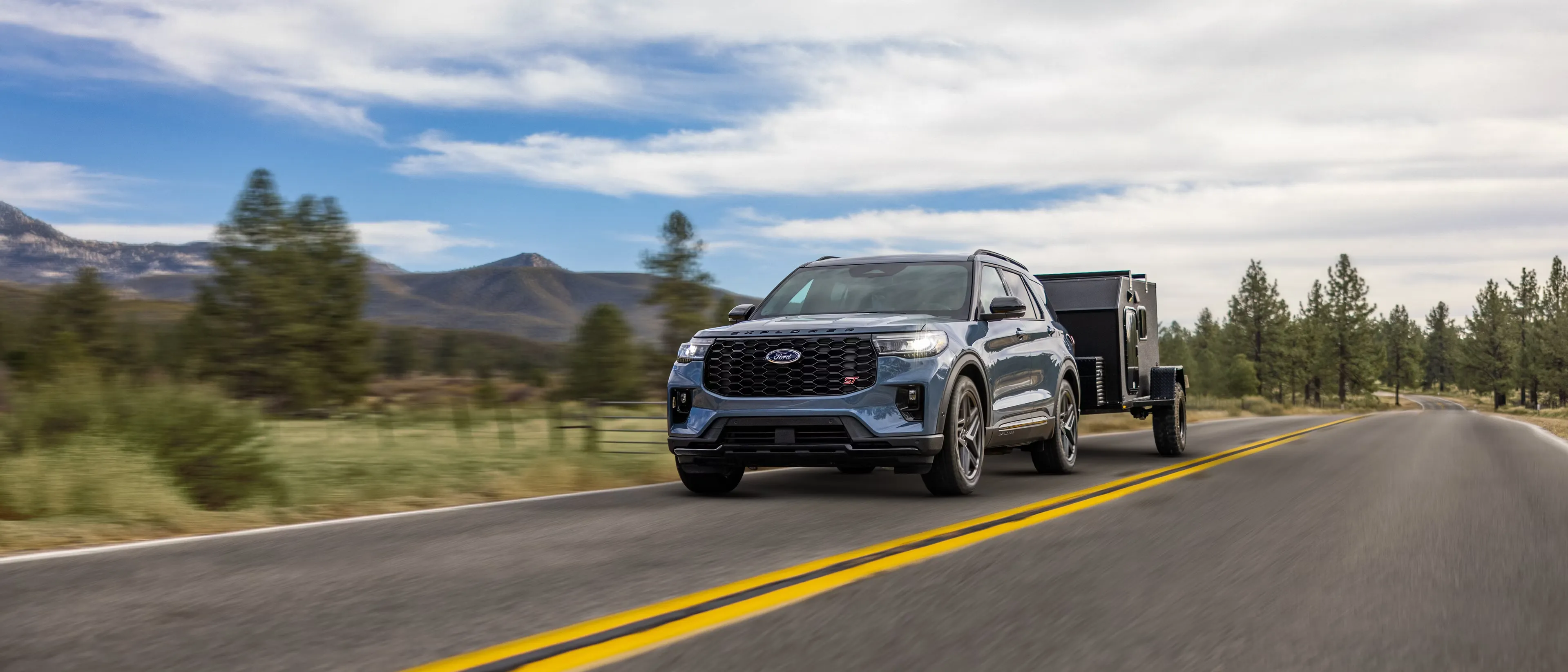 2026 Ford Explorer towing a utility trailer on the road.