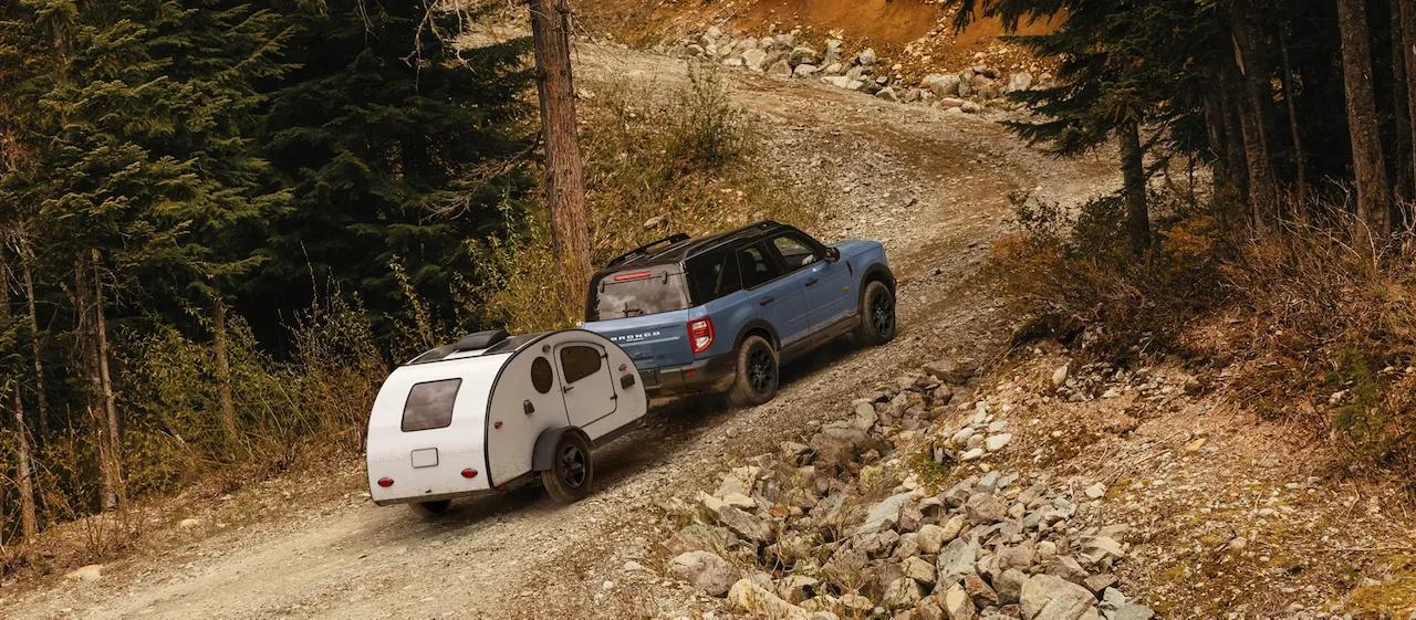 2026 Ford Bronco Sport towing a tent trailer on a rocky trail.