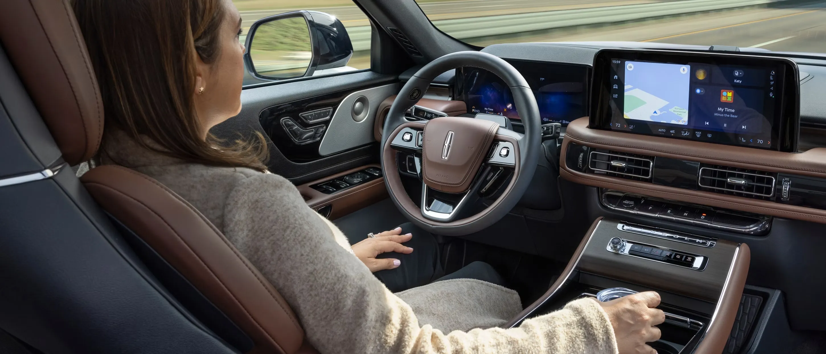Driver behind the wheel of the 2026 Lincoln Aviator with navigation system.