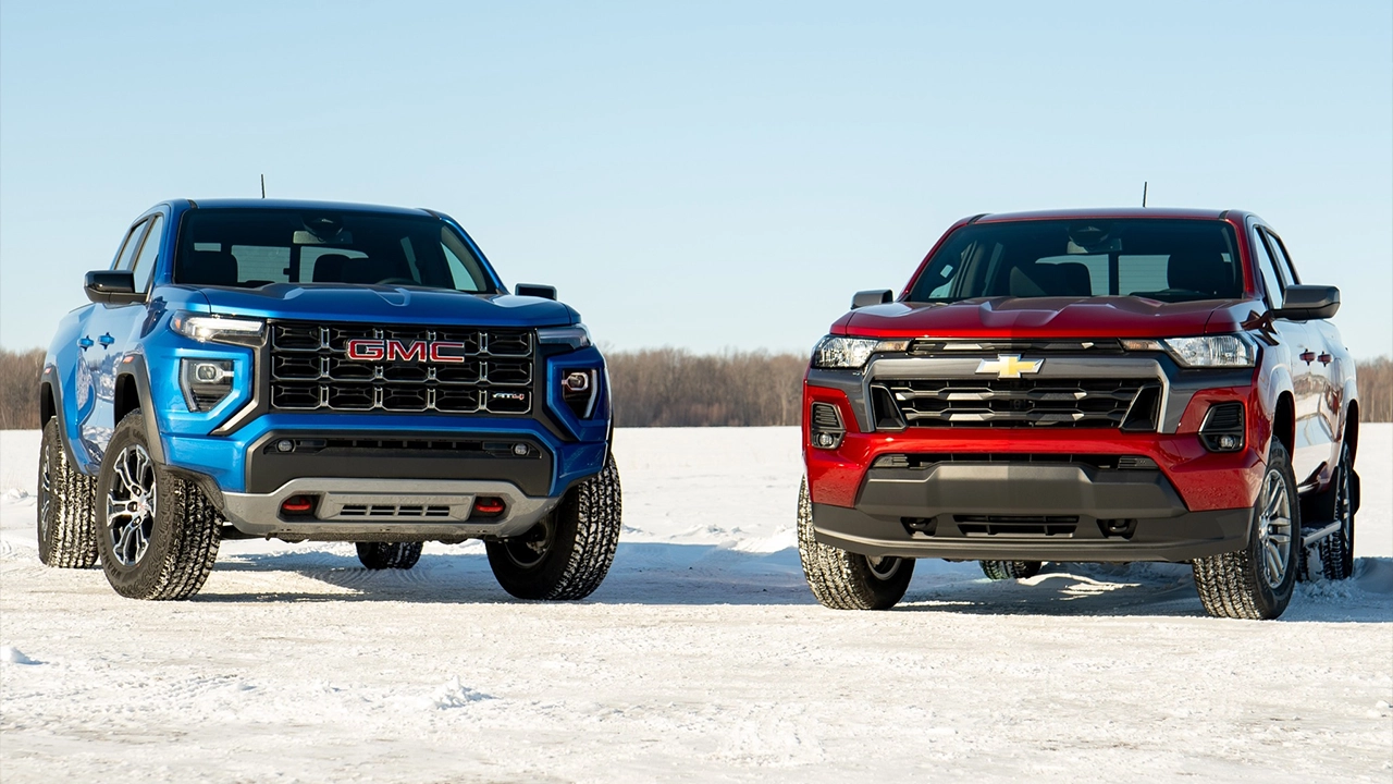 GMC Canyon 2026 bleu et Chevrolet Colorado 2026 rouge &mdash; m&ecirc;me plateforme, deux caract&egrave;res. C&ocirc;te &agrave; c&ocirc;te sur un lac gel&eacute;