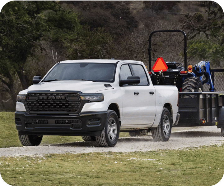 Vue 3/4 avant et latérale d'un RAM 1500 remorquant une roulotte avec tracteur pour travail