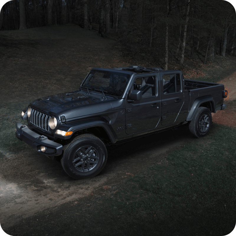 Gray Jeep Gladiator in dark forest.