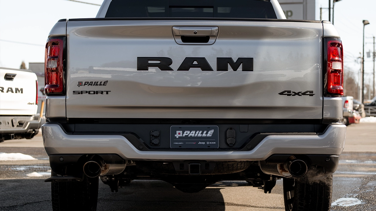 Vue arri&egrave;re d'un camion RAM 1500 Sport 4x4 argent dans le stationnement du concessionnaire Paill&eacute;, par temps hivernal.