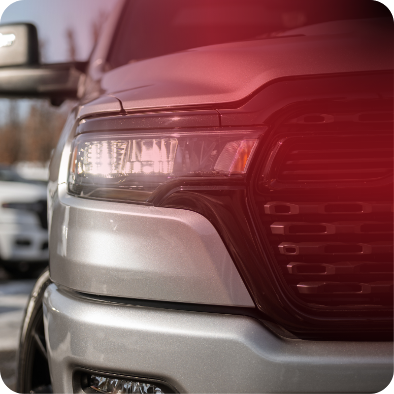 Close-up of the headlight and front grille of a silver 2026 RAM 1500.