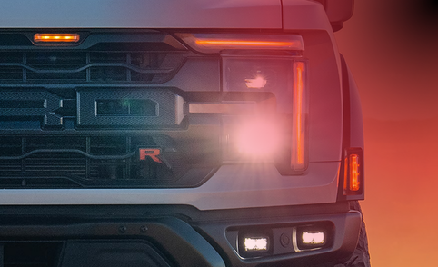 Close-up of the front end of a white 2026 Ford F-150 featuring its headlight and grille.