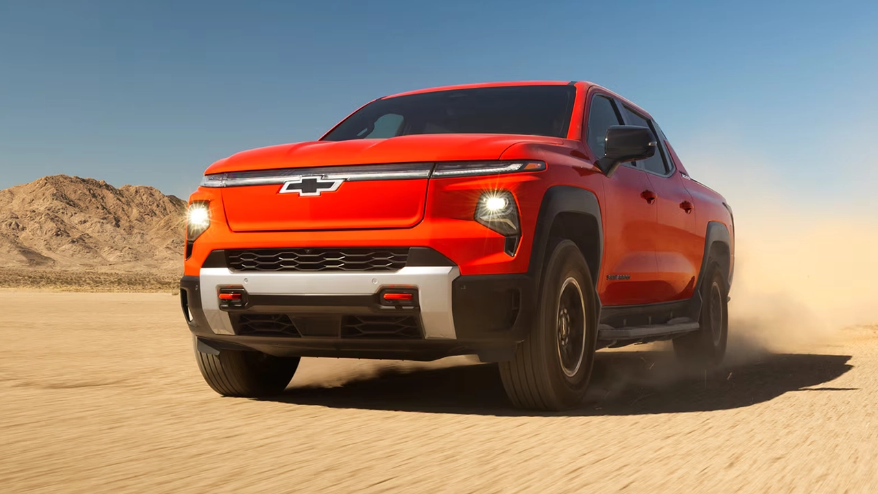Three-quarter front and side view of the 2026 Chevrolet Silverado EV at full throttle on a sandy road