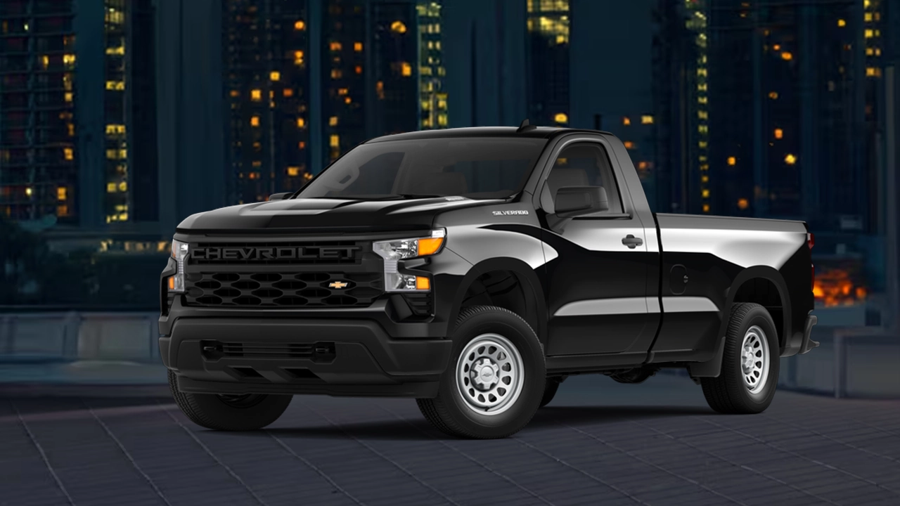 Vue 3/4 avant et latérale du chevrolet Silverado 1500 2026 et une cabine simple avec une vue sur ville le soir