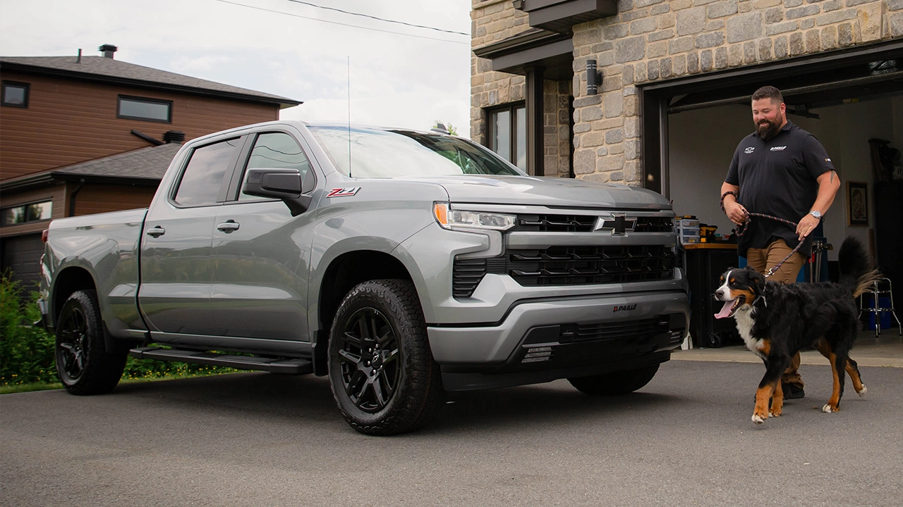 Vue latérale du Silverado 1500 RST 2026 stationné a la maison, avec un homme et son chien