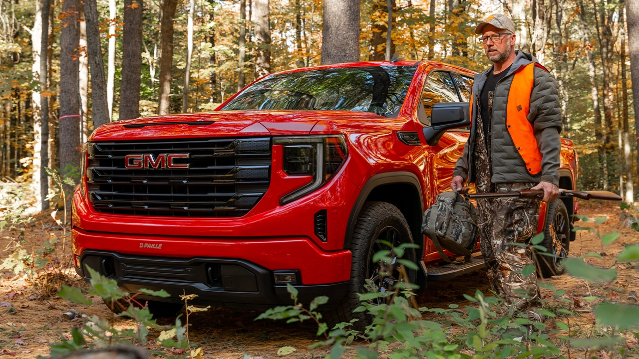 Vue 3/4 avant et latérale du Chevrolet Silverado 1500 2026 avec un homme et son équipement de chasse