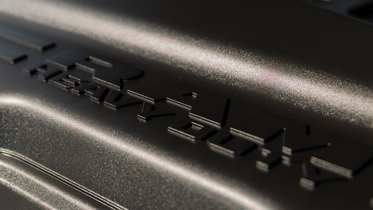 Close-up of a dark body with &ldquo;HEAVY DUTY&rdquo; embossing, with side lighting that highlights the texture and metallic sheen.