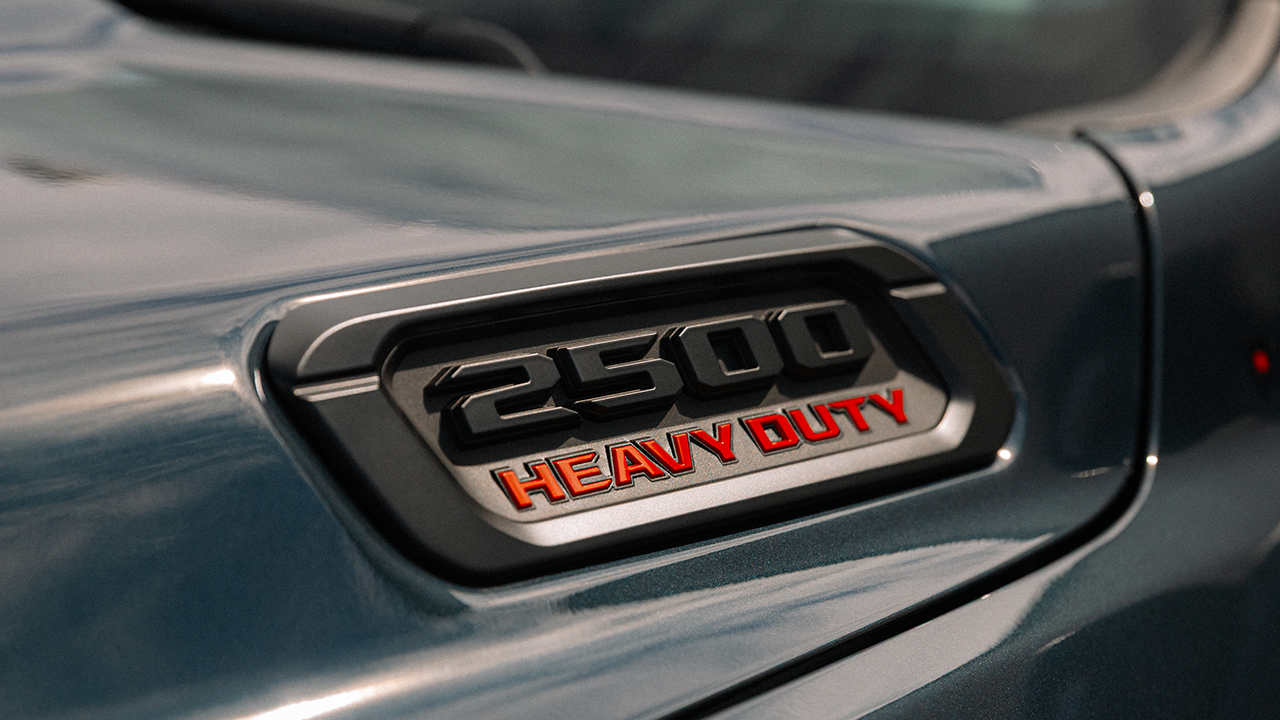 A close-up of the 2500 Heavy Duty badge with red lettering on the blue-gray body of a Ram pickup truck.