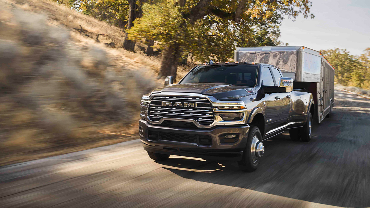 3/4 front and side view of the Ram 3500 on the road, towing a horse trailer