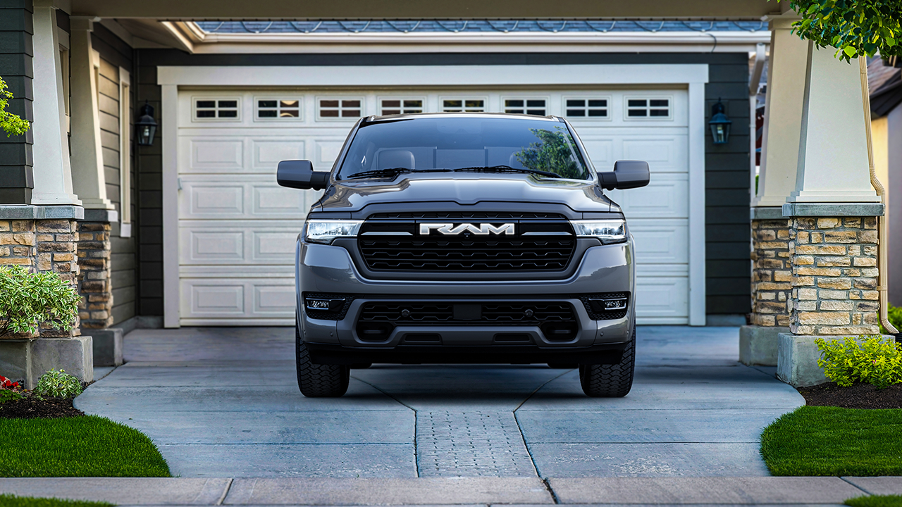 A gray Ram 1500 REV in front of a garage.