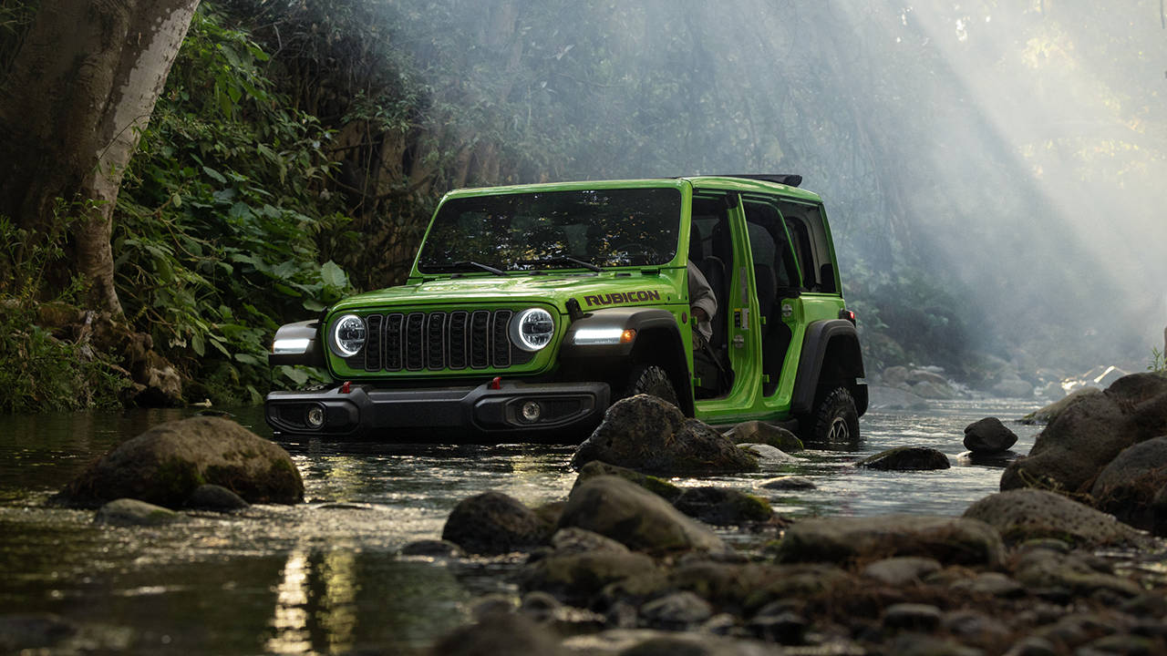 Jeep Wrangler driving through a puddle with its doors open