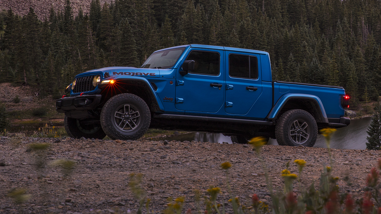 Side view of the 2026 Jeep Gladiator Mojave on a mountain road near a lake
