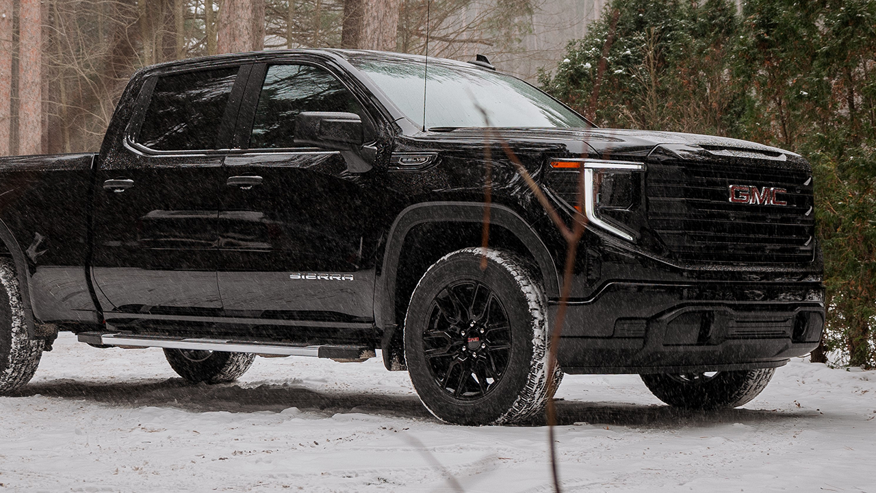 3/4 front and side view of the 2027 GMC Sierra in the woods during the first snowfall