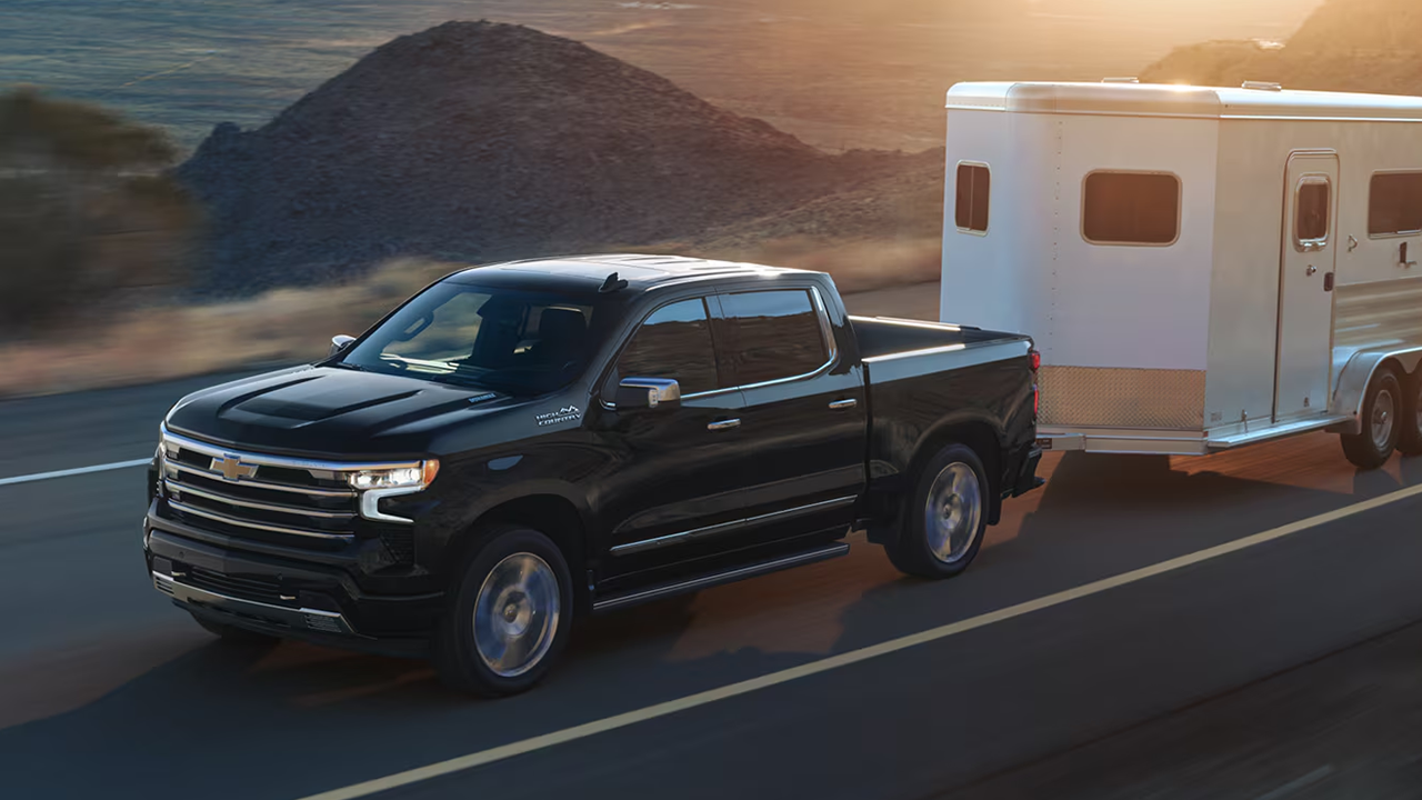 3/4 front and side view of the Chevrolet Silverado on the road, towing a trailer