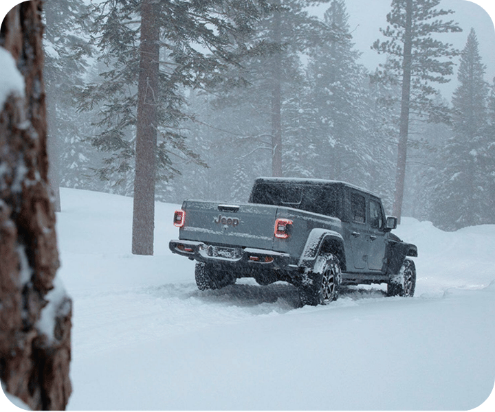 Rear view of the 2026 Jeep Gladiator on a mountain during a snowstorm