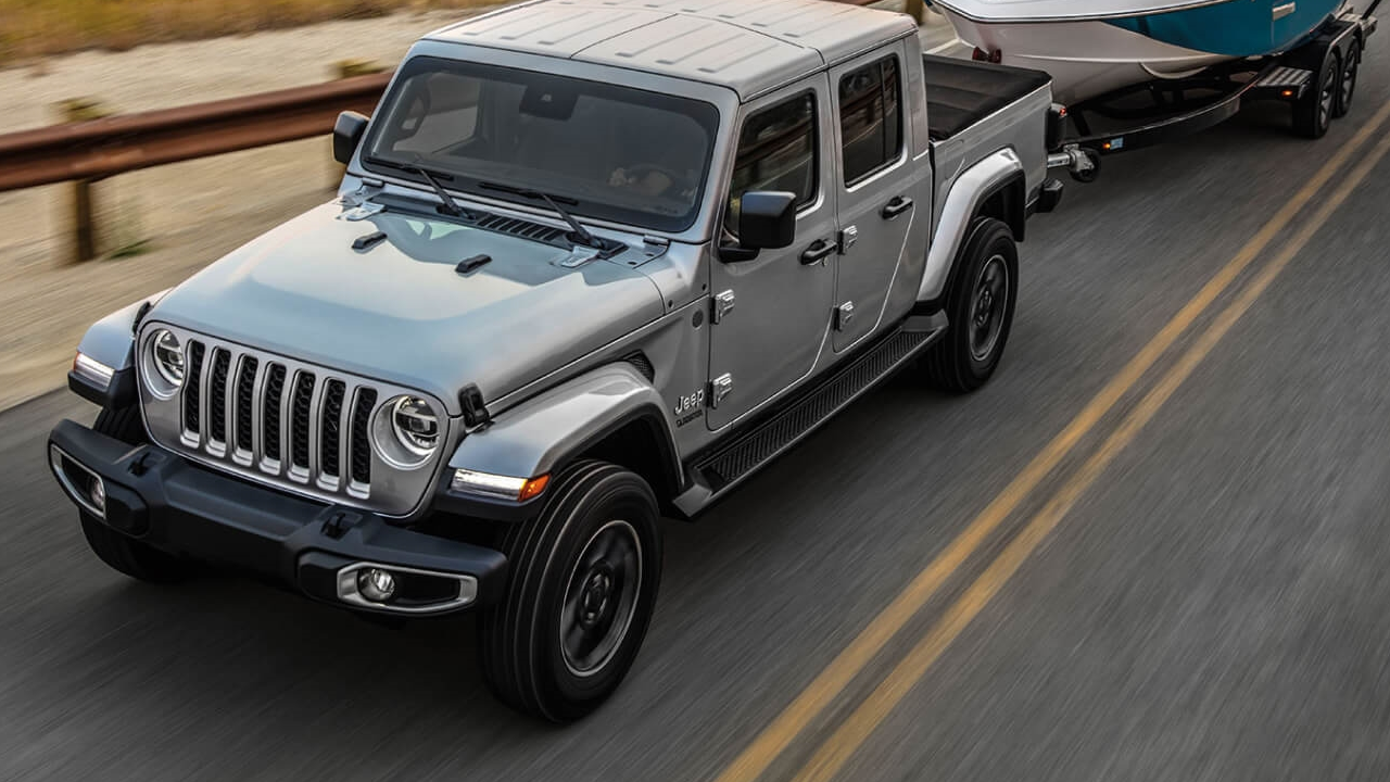 3/4 front and side view of the Jeep Gladiator on the road, towing a boat