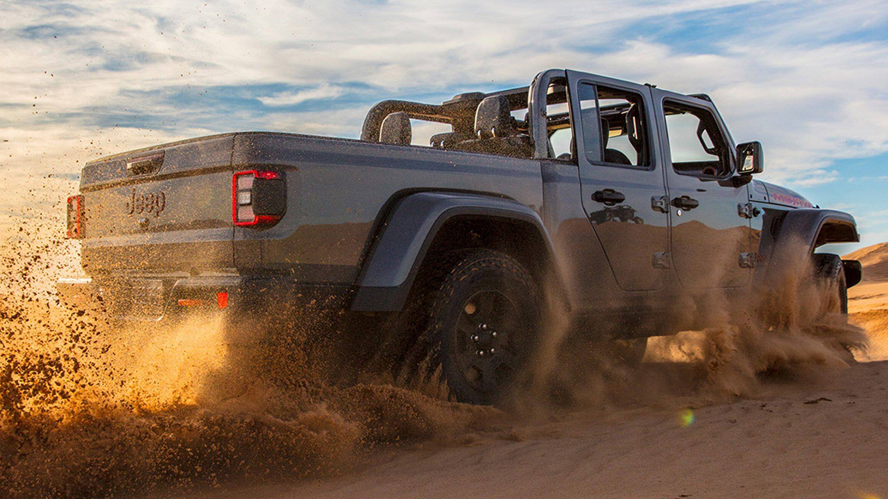 A close-up view of the rear of the 2026 Jeep Gladiator on a sandy road, going full throttle