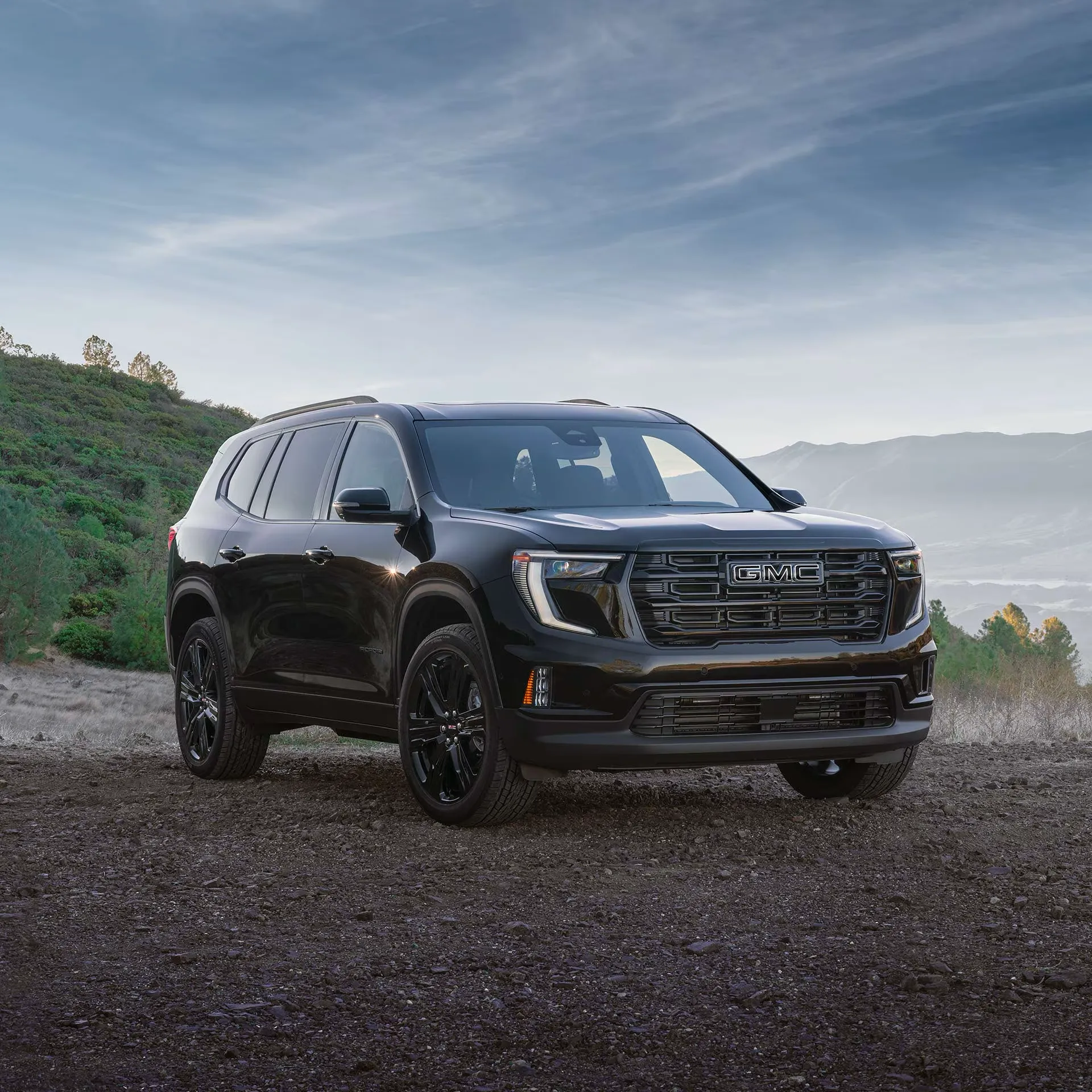 3/4 front view of the black 2026 GMC Acadia on a dirt road