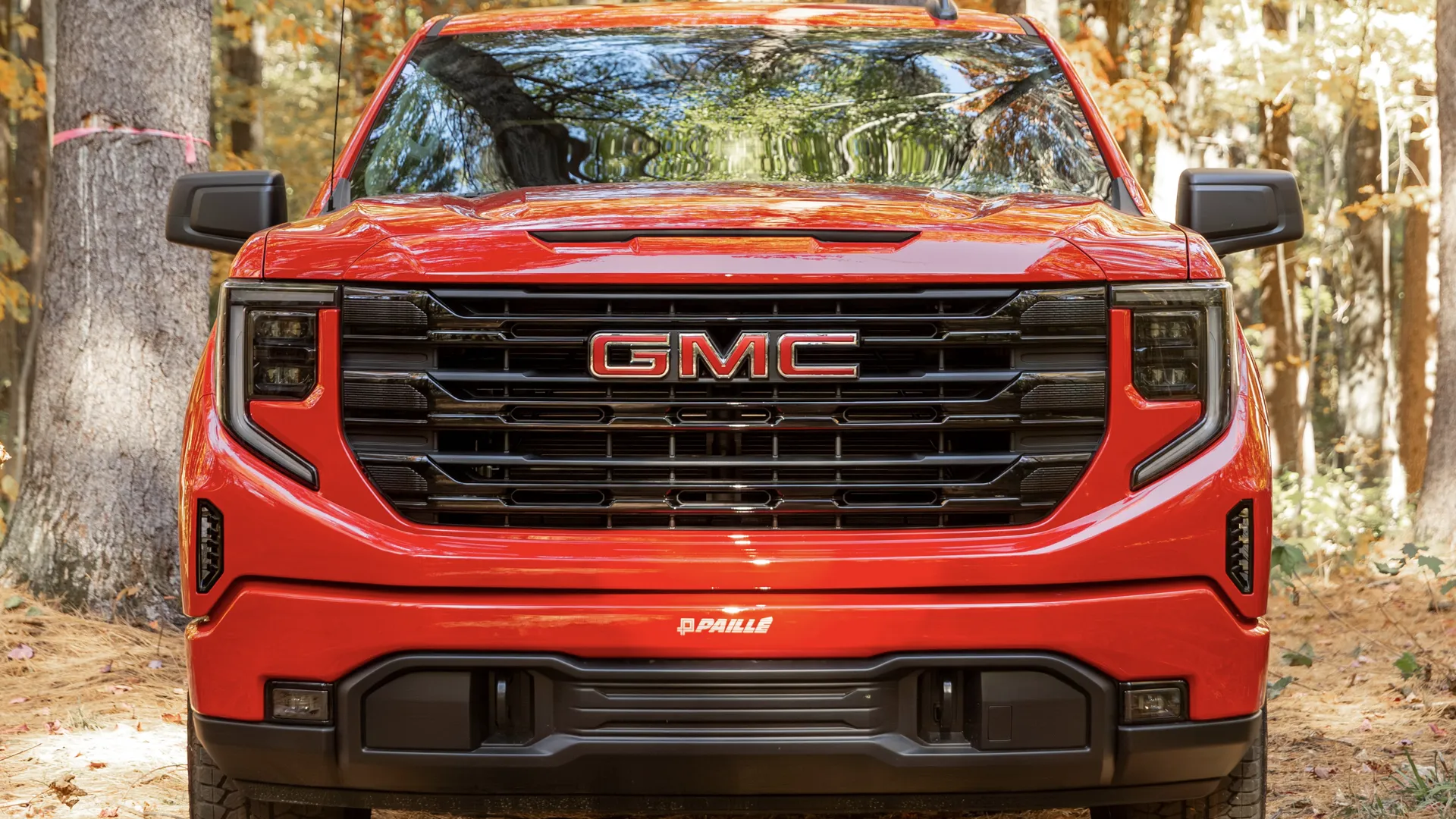 Close-up view of a red GMC Sierra 1500 in the forest.