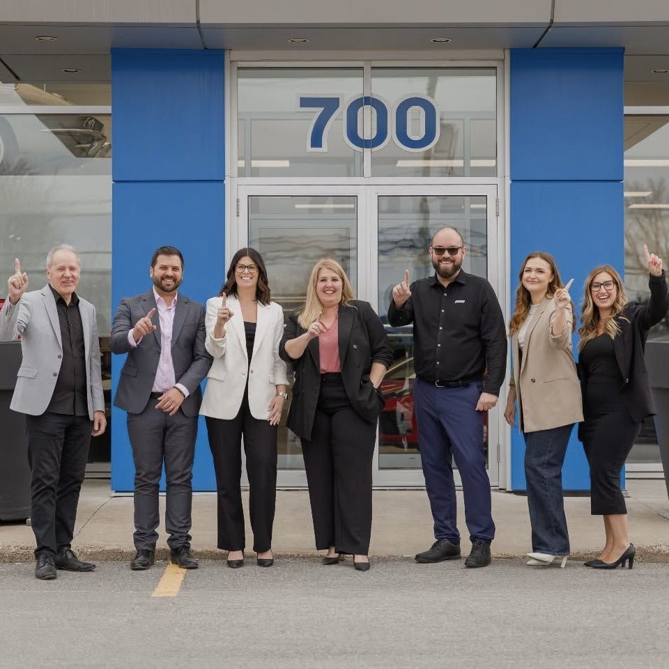 Team of Paillé advisors smiling in front of the dealership entrance.