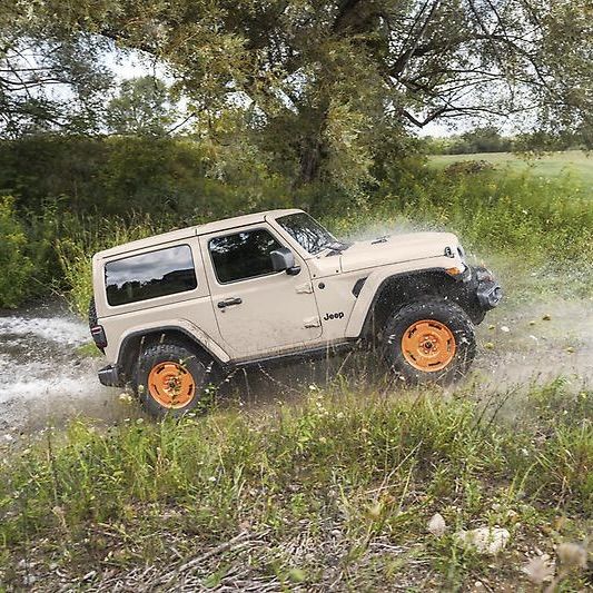 Jeep Wrangler Sarge crossing a stream in the forest.